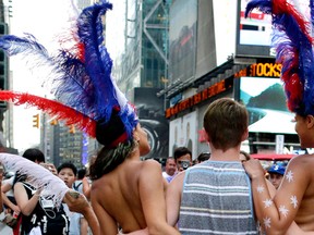 In this July 28, 2015 file photo, a tourist poses for a photo with two women clad in thongs and body paint in New York's Times Square. (AP Photo/Julie Jacobson, File)