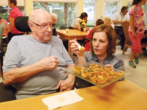 Ty Cumming, director of life enrichment at Finlandia Village, gives resident Jens Krejlgaard a piece of a butter tart at the Great Finlandia Butter Tart Bake off at Finlandia Village on July 21. (John Lappa/Sudbury Star)