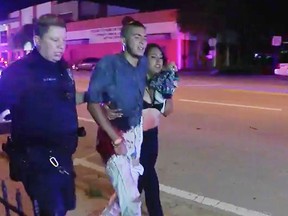 An injured man is escorted out of the Pulse nightclub after a shooting rampage, Sunday morning June 12, 2016, in Orlando, Fla. (AP Photo/Steven Fernandez)