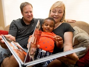 Joanne Currie, Dwayne Von Sprecken and their son Jacob Currie, 19 months old, look at a family album at their home in Sherwood Park on Monday June 27, 2016. The couple adopted Jacob through an open private adoption. Photo by David Bloom