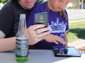 Colton Smith and his sister Cali, 9, play Pokémon Go in the Rebound Sarnia Lambton parking lot Friday morning. The youth agency hosted its first "lure drop" event for local Pokémon Go chasers Friday. (Barbara Simpson/Sarnia Observer/Postmedia Network)