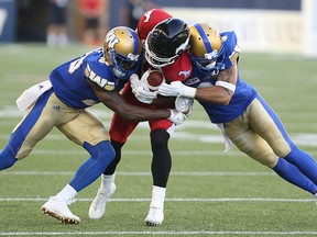 Calgary Stampeders receiver Marquay McDaniel is sandwiched by Kevin Fogg (left) and Macho Harris during CFL action on Thursday night. Harris was later injured and left the game. (Kevin King/Winnipeg Sun)