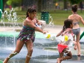 Jazmine Henry, 8, targets her little sister Alyssa, 5, with some water as they play at the Gibbons Park splash pad this week. George Clark has discovered, however, that London?s recent high temperatures can?t top the deadly steel-twisting, crop-wilting heat wave that rolled into the city in July, 1936. (MIKE HENSEN, The London Free Press)