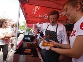 Mayor John Tory helps raise money for Sick Kids Hospital with Alexa Bogoslowski at Francy Franks gourmet hotdogs on College St. on national HotDog Day. Friday July 22, 2016. Jack Boland/Toronto Sun/Postmedia Network