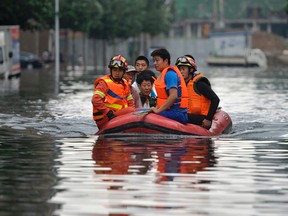 In this Thursday, July 21, 2016, photo, rescuers use a raft to transport people along a flooded street in Shenyang in northeastern China's Liaoning Province. Dozens of people have been killed and dozens more are missing across China after a round of torrential rains swept through the country earlier this week, flooding streams, triggering landslides and destroying houses. (Chinatopix Via AP)