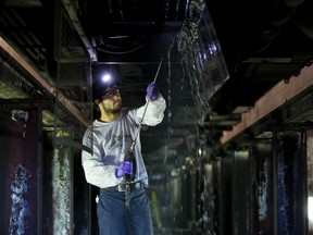 TTC Vehicle Repairperson Anthony Schembri cleans the condenser of an air conditioning unit at the bottom of a TTC subway car at TTC's Greenwood subway yard in Toronto, Ont. on Wednesday July 20, 2016. Ernest Doroszuk/Toronto Sun/Postmedia Network