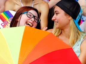 Amber Hamilton, left, of Trenton and Nikita Carr of Belleville laugh while sitting behind a rainbow-coloured umbrella the Belleville Pride Party in the Park Saturday. Hundreds of people took part in a parade and party, calling for a society that accepts everyone regardless of sexual orientation or gender identity.