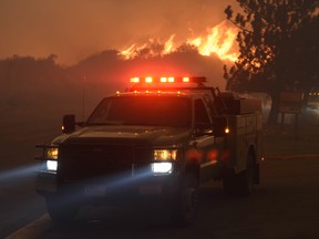 A fast burning wildfire chases down a couple of engines down Sand Caynon, near the Bear Divide in the Angeles National Forest, Calif.,  Saturday, July 23, 2016. Hundreds of county and Angeles National Forest firefighters battled the blaze, aided by three dozen water-dropping helicopters and retardant-dropping airplanes. The fire erupted Friday afternoon in the Sand Canyon area of suburban Santa Clarita near State Route 14 as the region was gripped by high heat and very low humidity. Winds pushed it into the adjacent Angeles National Forest. (AP Photo/Ryan Babroff)