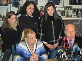 In this Friday Feb. 12, 2016 photo, Sarra Elizabeth Gilbert, center, is shown standing between her sisters Stevie Smith, left, and Sherre Gilbert, right, as her mother Mari Gilbert, seated left, and attorney John Ray, seated right, hold a press conference about Shannan Gilbert, a Jersey City, N.J., prostitute whose remains led to the discovery of 10 sets of human remains strewn along Long Island’s Gilgo Beach. Police say Mari Gilbert was found dead in her apartment Saturday, July 23, 2016, and Sarra Gilbert has been charged in the death of her mother. (AP Photo/Frank Eltman, File)