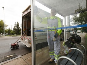 Edmonton Transit System utility workers Robert Young (left) and Pono Vey replace a broken glass panel at a bus shop on 107 Avenue near 120 Street in Edmonton, on Wednesday, July 20, 2016. Ian Kucerak / Postmedia