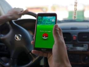 Egyptian dentist Mark Shehata, 24, uses the "Pokemon Go" mobile phone application while driving in Cairo July 20, 2016. (AP Photo/Amr Nabil)
