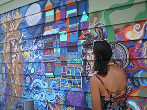 Artist Michelle Parboosingh works on her mural at the corner of Division and York streets. (Victoria Gibson/For The Whig-Standard)