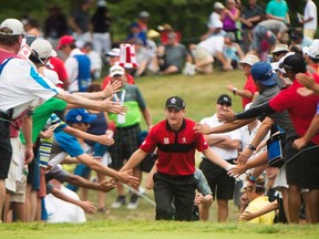 Jared du Toit, of Canada high fives fans in the crowed as he makes his way to the second tee box during the final round at the Canadian Open in Oakville, Ont., on July 24, 2016. (THE CANADIAN PRESS/Nathan Denette)
