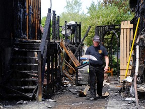 Senior fire prevention officer John Lake retrieves residents' belongings Sunday from one of two homes damaged extensively by a Saturday-night fire in Belleville. There were no human injuries but one cat died.