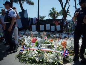 Nice's municipal police members stand by spray of flowers at they attend a wreath-laying ceremony on the initiative of the municipal police in tribute to the victims of the attack of July 14 in Nice, southeastern France. (BERTRAND LANGLOIS/Getty Images)