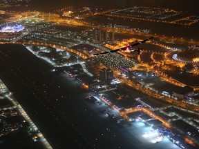 The Solar Impulse 2 plane, top right, flies over flies by Al-Bateen Executive Airport, bottom, and the Sheikh Zayed Grand Mosque, top left, in Abu Dhabi, United Arab Emirates, shortly before landing Tuesday, July 26, 2016. The world's first ever round-the-world flight to be powered solely by the sun's energy made history with its landing in the Emirati capital, where it first took off more than a year ago. (AP Photo/Adam Schreck)