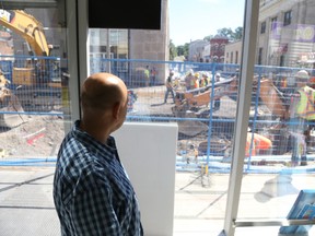 Jason Miller/The Intelligencer
Faisal Asad looks out the window of the Front Dollar Store Tuesday morning as Corcoran Excavation crews get back to work as pedestrians went about their routine, hours after a mass exodus was triggered downtown due to excavation equipment ruptured a gas line. The leak happened just steps away from Asad's storefront.