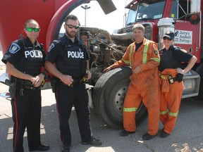 St. Thomas Police and Ontario Ministry of Transportation inspectors stand next to a dump truck pulled off the road for loose steering components.