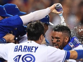 Toronto Blue Jays’ Devon Travis, right, is congratulated by teammates after he scored the winning run on a wild pitch during MLB action in Toronto on Tuesday, July 26, 2016. (THE CANADIAN PRESS/Frank Gunn)