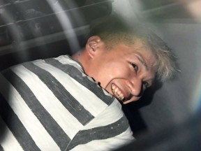 Satoshi Uematsu, the suspect of Tuesday's knife attack at a home for the mentally disabled, sits inside a police van as he leaves a police station in Sagamihara, outside Tokyo to be sent to prosecutors Wednesday, July 27, 2016. The deadliest mass killing in Japan in the post-World War II era raised questions about whether Japan's reputation as one of the safest countries in the world is creating a false sense of security. (Naohiko Hatta/Kyodo News via AP)