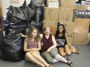 Shera Lumsden of MusicMates, centre, sits in her building in Kingston, Ont. on Tuesday, July 26, 2016 with individual support workers Samsara Boots, left, and Inaara Manji with some of the bags of donated items that will help pay for support workers for the music programs they run. Michael Lea The Whig-Standard Postmedia Network