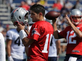 New England Patriots quarterback Jimmy Garoppolo, left, removes his helmet as quarterback Tom Brady, right, winds up for a pass during training camp Thursday, July 28, 2016, in Foxborough, Mass. (AP Photo/Steven Senne)