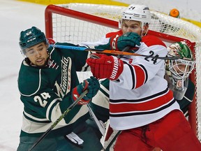 Minnesota Wild defenceman Matt Dumba, left, keeps Carolina’s Brad Malone occupied as Wild goalie Devan Dubnyk, right, peeks around them Saturday, March 19, 2016, in St. Paul, Minn. (AP Photo/Jim Mone)