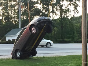 This Wednesday, July 27, 2016, photo provided by G. Ray Ault shows a vehicle on wires attached to a utility pole in Mendon, Vt. Police in Vermont say the car ended up almost vertical when the driver swerved quickly in response to her GPS ordering her to "turn around." (G. Ray Ault via AP)