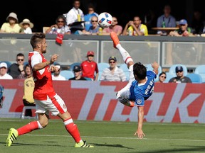 MLS all-star David Villa tries to hit a scissor kick next to Arsenal’s Mathieu Debuchy during the MLS all-star game on Thursday night. (AP)