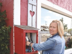 Richelle Jomha adds books to her mini library outside the Barn Owl on July 21. - Photo by Marcia Love