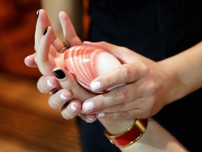 In this July 27, 2016 photo, esthertician Carina Deppiesse, of Kohler Waters Spa, in Kohler WI, uses a Lava Shell as she demonstrates the All Things Scotland Body Treatment, during the annual International SPA Association event, in New York. (AP Photo/Richard Drew)