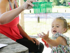 Many children showed up for the Perth Care for Kids’ New Kid’z Science & Sensory program last Wednesday, July 27 at the Mitchell Lions Park, giving youngsters (and some moms) the chance to play around in various goop and water. Julie Schoonderwoerd holds a strainer up so 20-month-old daughter Sadie can watch it fall through the cracks. ANDY BADER/MITCHELL ADVOCATE