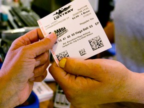 A customer purchases a Mega Millions lottery ticket at a store in Damariscotta, Maine, Friday, July 8, 2016. The jackpot for Friday's drawing has soared to over $500 million. (AP Photo/Robert F. Bukaty)