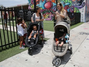 Vanessa Gomez, 33, left, with her son Ezra, 2, and her friend Cristy Fernandez, 33, with her 9-month-old- son River, of Miami, walk in the Wynwood neighborhood of Miami, Friday, July 29, 2016. Florida health officials said that four patients in Florida infected with the Zika virus were infected in the Wynwood area. These cases are believed to have caught the virus locally through mosquito bites. Gomez said the news is "scary but we cannot stop living our lives." To the left are Olivia Gomez, 5, and Kaly Fernandez. (AP Photo/Marta Lavandier)