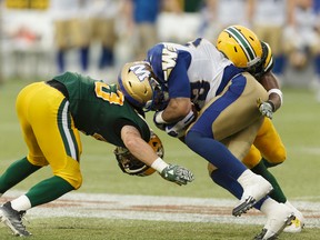 Edmonton's Neil King (43) and Winnipeg's Andrew Harris (33) collide during a CFL football game between the Edmonton Eskimos and the Winnipeg Blue Bombers at Commonwealth Stadium in Edmonton, on Thursday, July 28, 2016. Ian Kucerak / Postmedia (For Edmonton Journal/Sun story by Gerry Moddejonge)