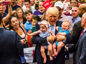 Republican presidential candidate Donald Trump kisses Kellen Campbell of Denver, while also holding Evelyn Keane of Castle Rock, Colo., during a campaign rally, Friday, July 29, 2016, in Colorado Springs, Colo. (AP Photo/Evan Vucci)