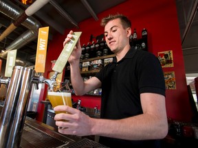 Marketing coordinator Jackson Stuart pours a pint of beer at Village Brewery in Calgary on July 18, 2016. The province is changing its beer tax system, replacing a graduated markup system for beers from B.C., Alberta and Saskatchewan with a flat $1.25-per-litre charge. Lyle Aspinall/Postmedia Network