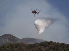 A firefighting helicopter drops water in Placerita Canyon at the Sand Fire on July 25, 2016 in Santa Clarita, California. (Photo by David McNew/Getty Images)