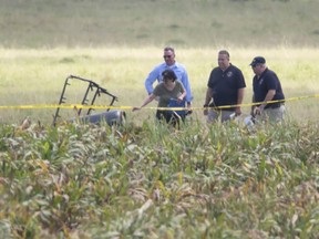 The partial frame of a hot air balloon is visible above a crop field as investigators comb the wreckage of a crash Saturday morning, July 30, 2016, near central Texas. Authorities say the accident caused a "significant loss of life." (Ralph Barrera/Austin American-Statesman via AP)