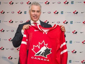 Dominique Ducharme holds up a Team Canada jersey after being named head coach of the 2016-2017 national junior team following a ceremony in Montreal, Monday, June 6, 2016. (THE CANADIAN PRESS/Graham Hughes)