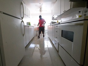 Menan Descollines walks through a flooded kitchen in a neighbour's apartment nearly twenty four hours after heavy rain left several units of a three storey walkup at 1170 Adelaide Street North with ankle-deep water throughout in London. (CRAIG GLOVER, The London Free Press)