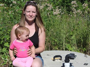 Samantha Reed/The Intelligencer
Hailee Daniels sits on top of the well outside of her home with her eleven-month-old daughter Bryndle Tuesday morning. Daniels says the well on her Massassauga Road home dried up last week, leaving her family without water for days.