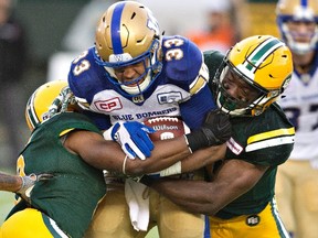 Winnipeg Blue Bombers Andrew Harris (33) is tackled by Edmonton Eskimos Cauchy Muamba (8) and Deon Lacey (40) during first half CFL action in Edmonton, Alta., on Thursday July 28, 2016. Harris isn't buying the suggestion Matt Nichols was first-time lucky in his 2016 debut with the Winnipeg Blue Bombers. THE CANADIAN PRESS/Jason Franson.