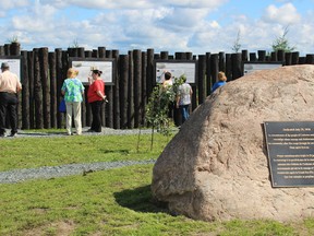 Members of the community look over the interpretive signs on display at the 1916 Fire Memorial.