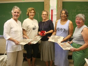 Volunteers hold up the clay poppies they are working on. (Justine Alkema/Clinton News Record)