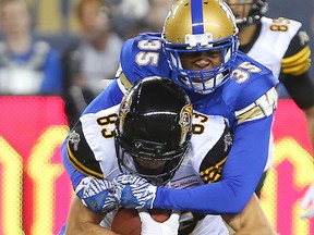 Hamilton Tiger-Cats wide receiver Andy Fantuz, left, is hauled down by Winnipeg Blue Bombers defensive back Terrence Frederick during their game in Winnipeg, on Aug. 3, 2016. (Brian Donogh/Winnipeg Sun/Postmedia Network)