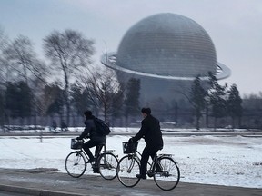 In this Feb. 23, 2016, file photo, North Koreans cycle past a planetarium at the Three Revolutions Exhibition Hall in Pyongyang, North Korea. North Korean space officials are hard at work on a five-year plan to put more advanced satellites into orbit by 2020, and don't intend to stop there: They're also aiming for the moon, and beyond. (AP Photo/Wong Maye-E, File)