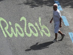 A man walks past the Rio2016 logo painted on a street in the Ipanema neighborhood on August 4, 2016 in Rio de Janeiro, Brazil. The Rio 2016 Olympic Games commence on August 5.  (Photo by Mario Tama/Getty Images)