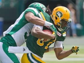 Saskatchewan Roughriders' Justin Cox (31) tackles Edmonton Eskimos' Derel Walker (87) during CFL action in Edmonton on June 18, 2016.