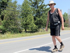 Keith Bourne walks along Highway 2 in front of the Treasure Island Marina in Kingston, Ont., on Thursday August 4, 2016. His journey started in Cornwall on July 31, and his goal is to walk 540km to Kitchener to gather donations for the physically disabled. Julia Balakrishnan for the Whig-Standard/Postmedia Network